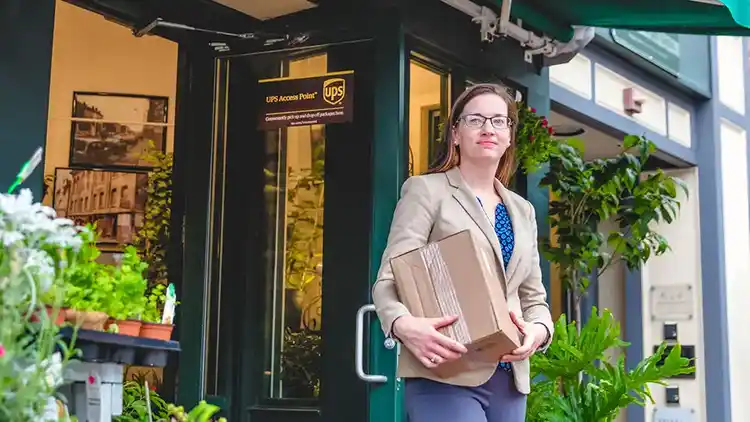 Propietario de una pequeña empresa deja un paquete para devolución en una ubicación UPS Access Point.